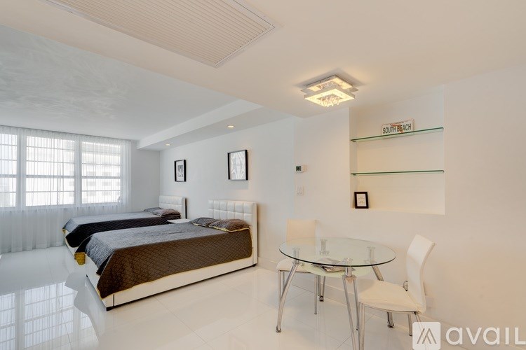 A bedroom with a bed, a glass table and chairs, and pictures on the wall.