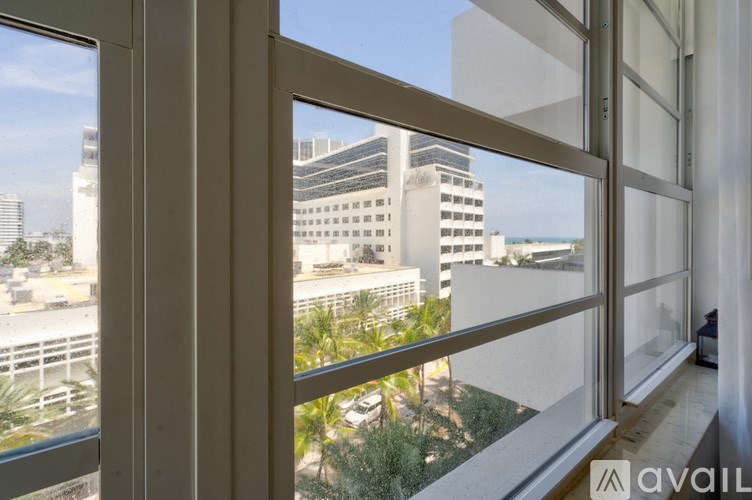 A window overlooks a cityscape with buildings and palm trees.