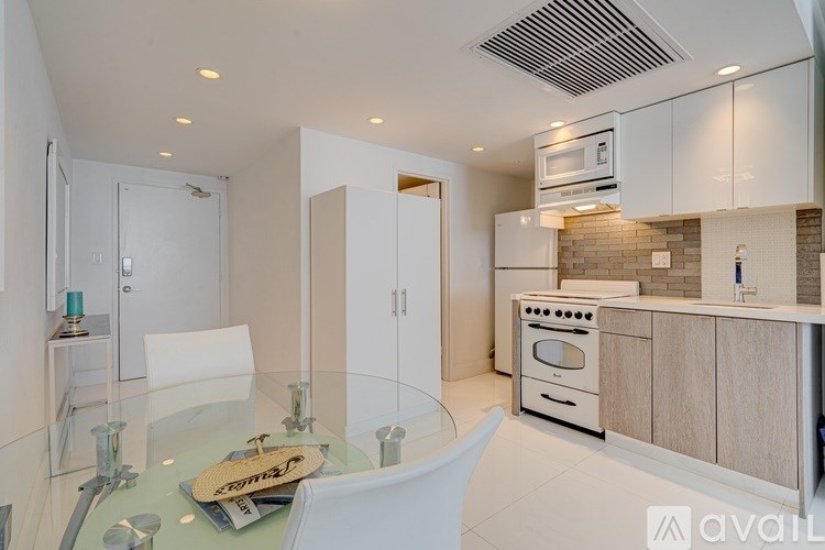 A modern kitchen with a glass table and white chairs.