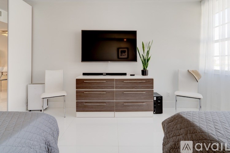 A modern bedroom with a large bed, a television, and a wooden cabinet.