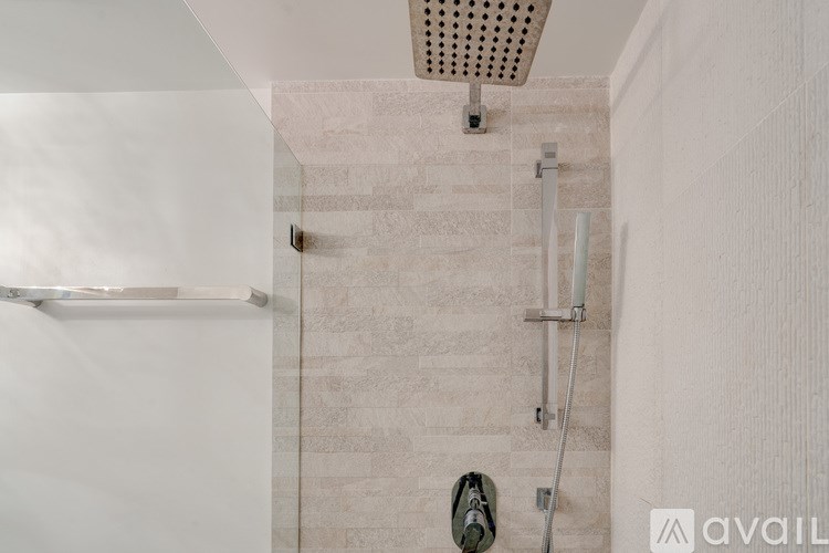 A bathroom with a shower and a white wall.