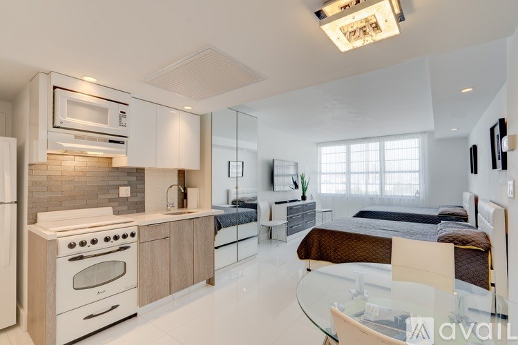 A modern kitchen with a glass table and a bedroom in the background.