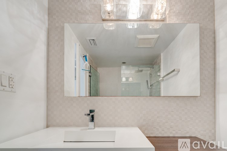 A bathroom with a white sink and a large mirror.