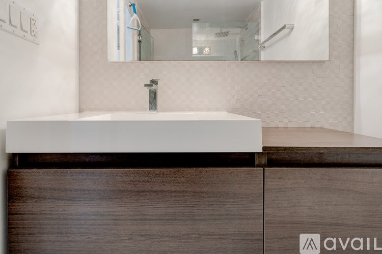 A white sink in a modern bathroom with a wooden counter.
