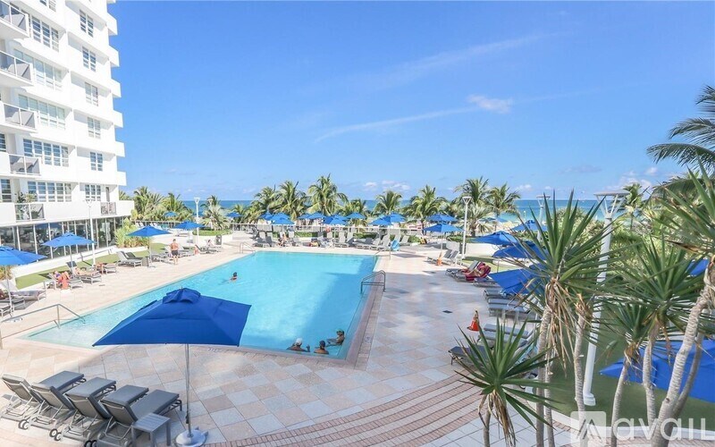 A large swimming pool surrounded by palm trees and lounge chairs.