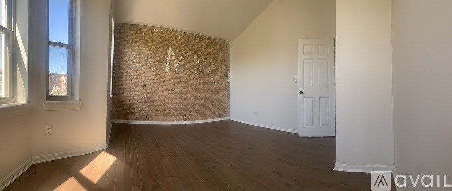 A room with a brick wall and wooden flooring is available for rent.