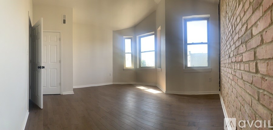 A room with a brick wall and wooden floors is available for rent.