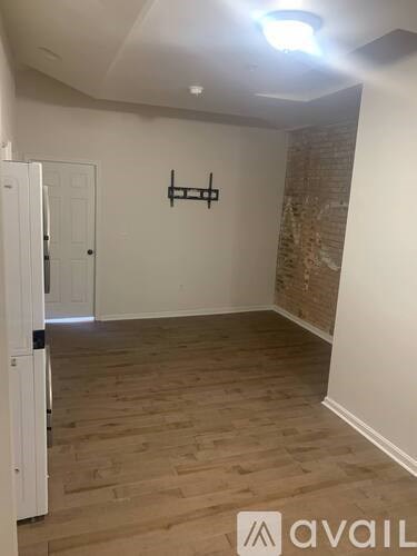 A room with wooden flooring and a brick wall.