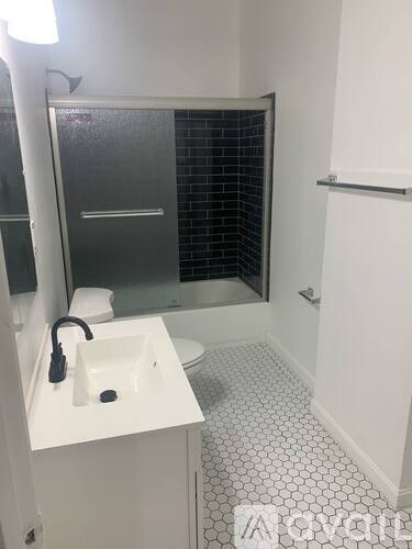 A white sink with a black faucet is in a white bathroom.