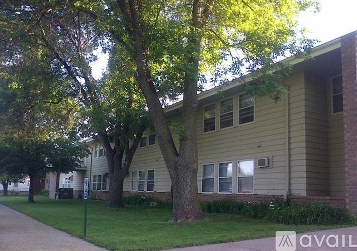 A tree in front of a building with a sign that says "available".
