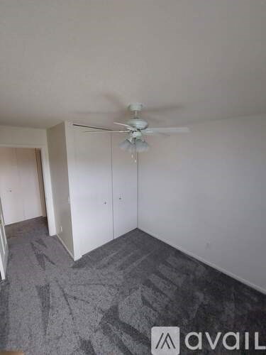 A room with a ceiling fan and carpeted floor.