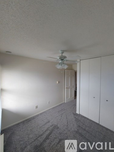A room with a carpeted floor and a ceiling fan.