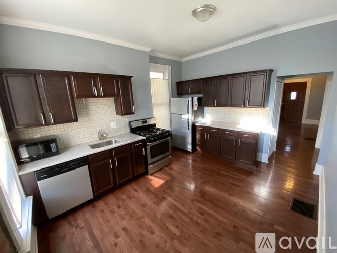 A kitchen with wooden floors and brown cabinets.