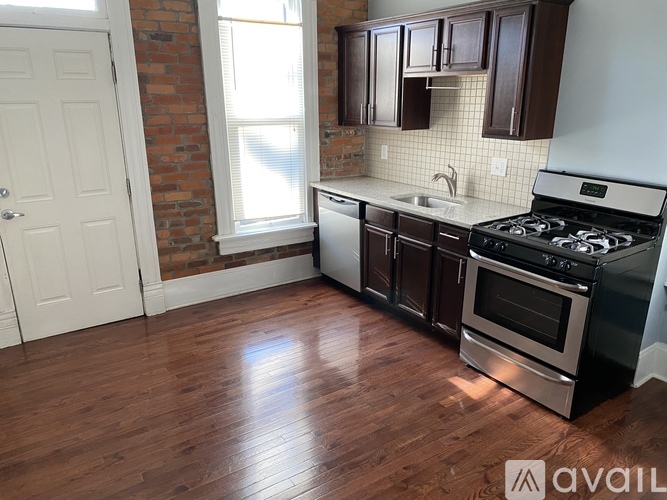 A kitchen with a stove, sink, and cabinets.