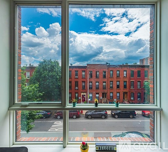 A view from a window of a street with cars and a red brick building.