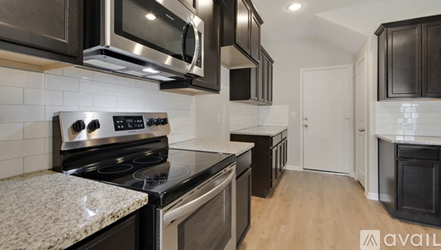 A modern kitchen with dark brown cabinets and stainless steel appliances.