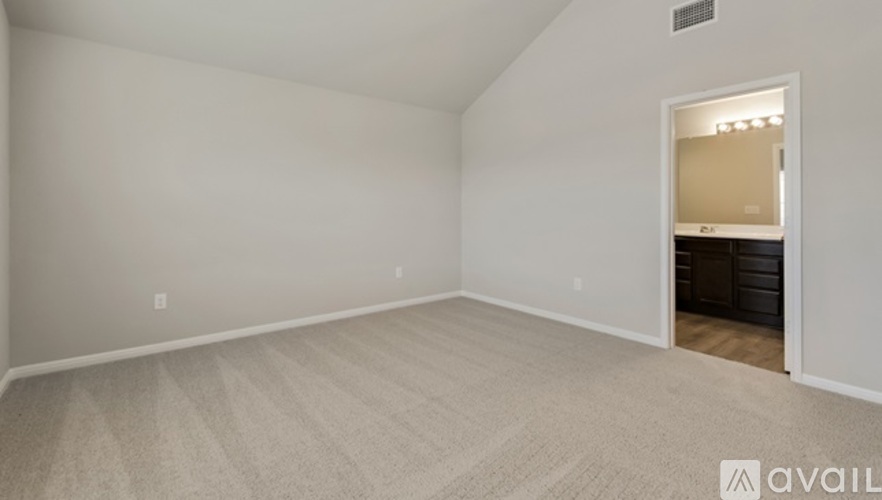 A spacious room with a carpeted floor and a doorway leading to another room.