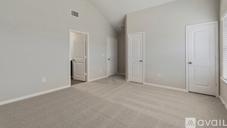 A room with beige carpet and three white doors.