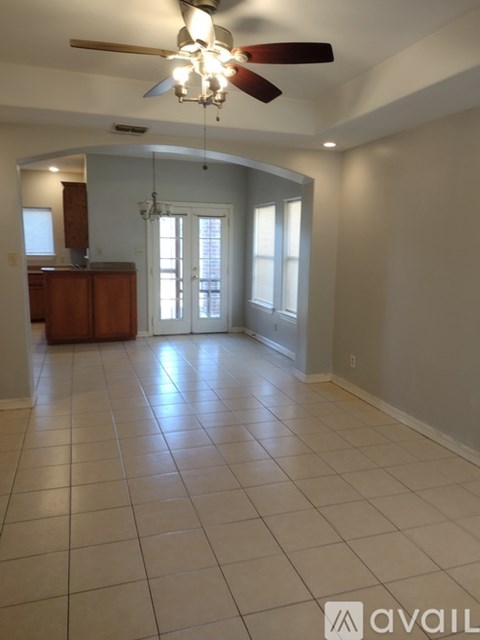 A spacious room with a ceiling fan and tiled flooring.