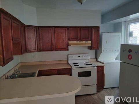 A kitchen with wooden cabinets and a white stove top oven.