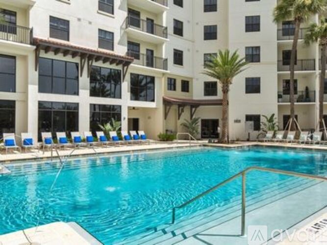 A large swimming pool in front of a white apartment building.