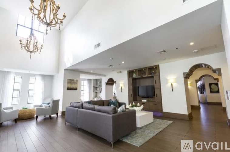 A large, well-lit living room with a grey sofa and a chandelier.