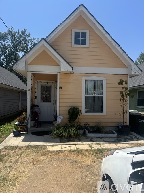 A small yellow house with a white door and a window.