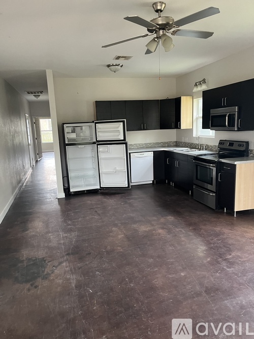 A kitchen with black cabinets and a refrigerator with the door open.
