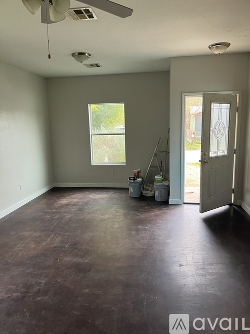 A room with a brown floor and a ceiling fan.