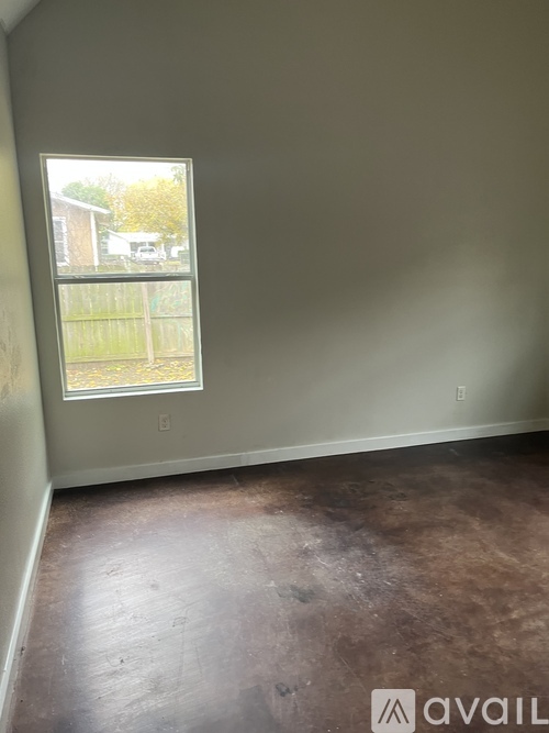 A room with a window and a brown floor.