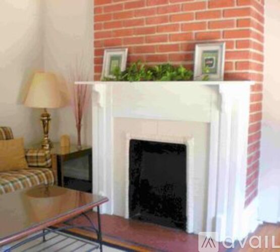 A white fireplace with a brick wall above it.