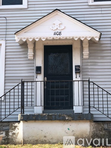 A house numbered 1108 has a black door and a balcony with a metal railing.