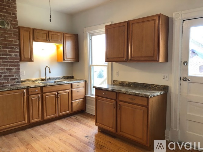 A kitchen with wooden cabinets and a brick wall.