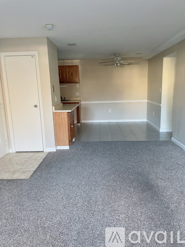 A room with a carpeted floor and a ceiling fan.