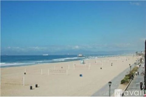 A beach with people walking and a clear blue sky.