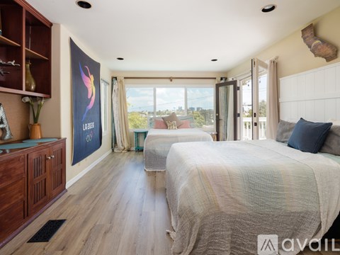 A bedroom with two beds and a large window overlooking the outdoors.