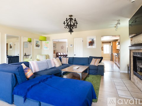 A living room with a blue couch and a chandelier.