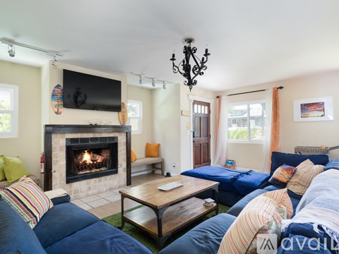 A living room with a fireplace and a television mounted above it.