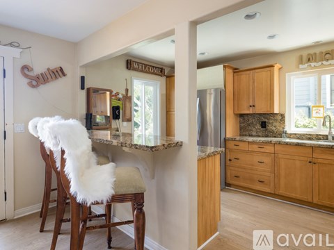 A kitchen with a bar stool and a chair with a white furry seat cushion.