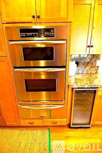 A stainless steel oven is built into a wooden cabinet.