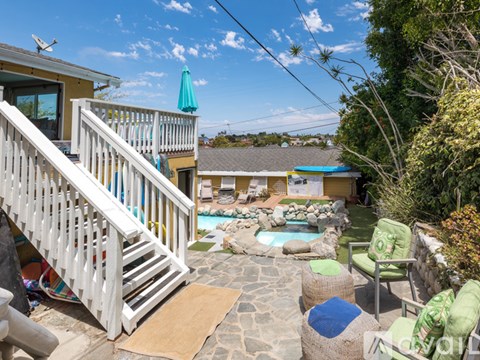 A sunny backyard with a pool and patio furniture.