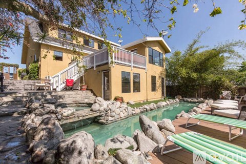 A yellow house with a pool in front.