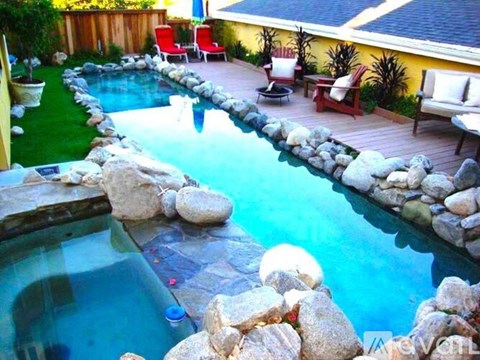 A pool with a rocky edge and a waterfall.