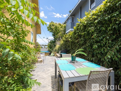 A patio with a table and chairs surrounded by greenery.