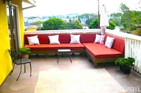 A balcony with a red couch and a white fence.