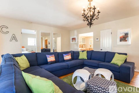 A living room with a blue couch and a chandelier.