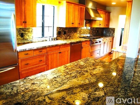A kitchen with granite countertops and wooden cabinets.