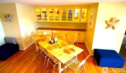 A dining room with a table set for two and chairs around it.