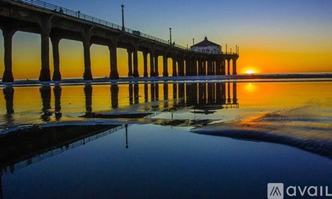 A pier extends into a calm body of water at sunset.