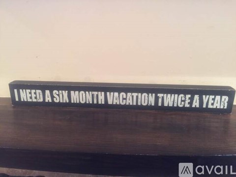 A sign that says "I need a six month vacation twice a year" is displayed on a wooden surface.